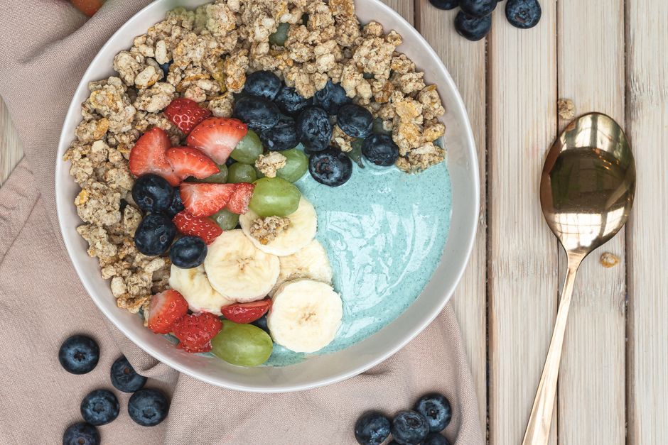 Bol de petit-déjeuner délicieux avec du yaourt, du granola, des fruits frais et de la spiruline bleue.