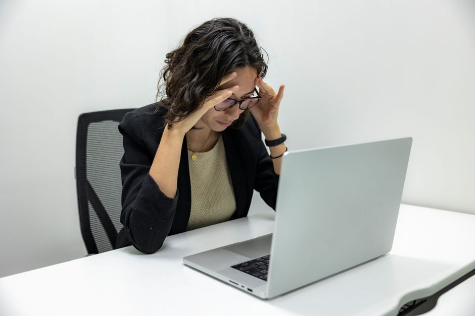 Une jeune femme éprouvant du stress et de la fatigue tout en travaillant sur son ordinateur portable dans un cadre de bureau.