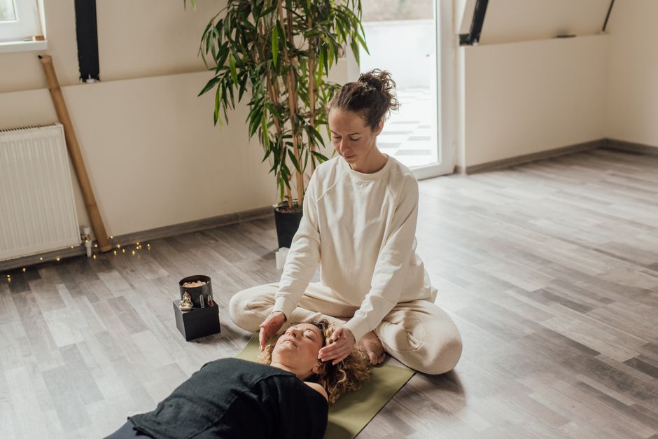 Une séance de Reiki apaisante à l'intérieur avec un thérapeute et un patient sur un tapis de yoga, axée sur l'énergie de guérison.
