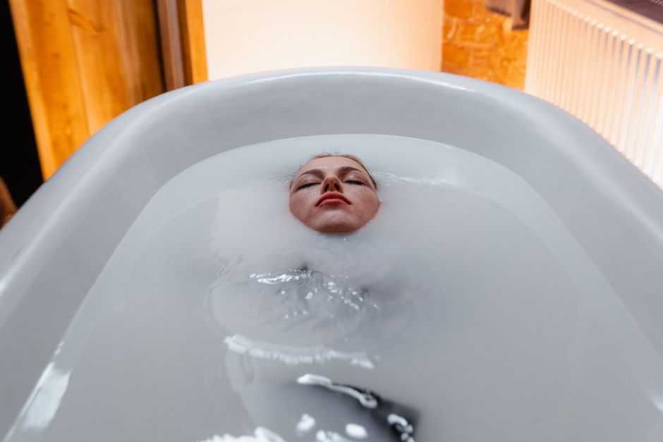 Une femme flottant paisiblement dans une baignoire, créant une atmosphère sereine et calmante.