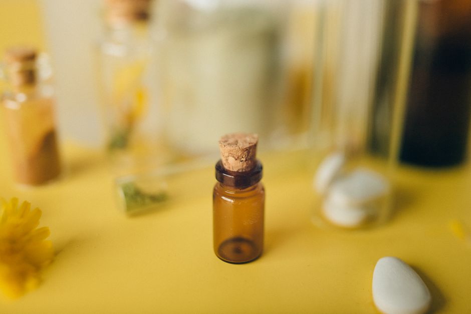 Une petite bouteille en verre avec un bouchon sur un fond jaune vif, entourée d'éléments doux.